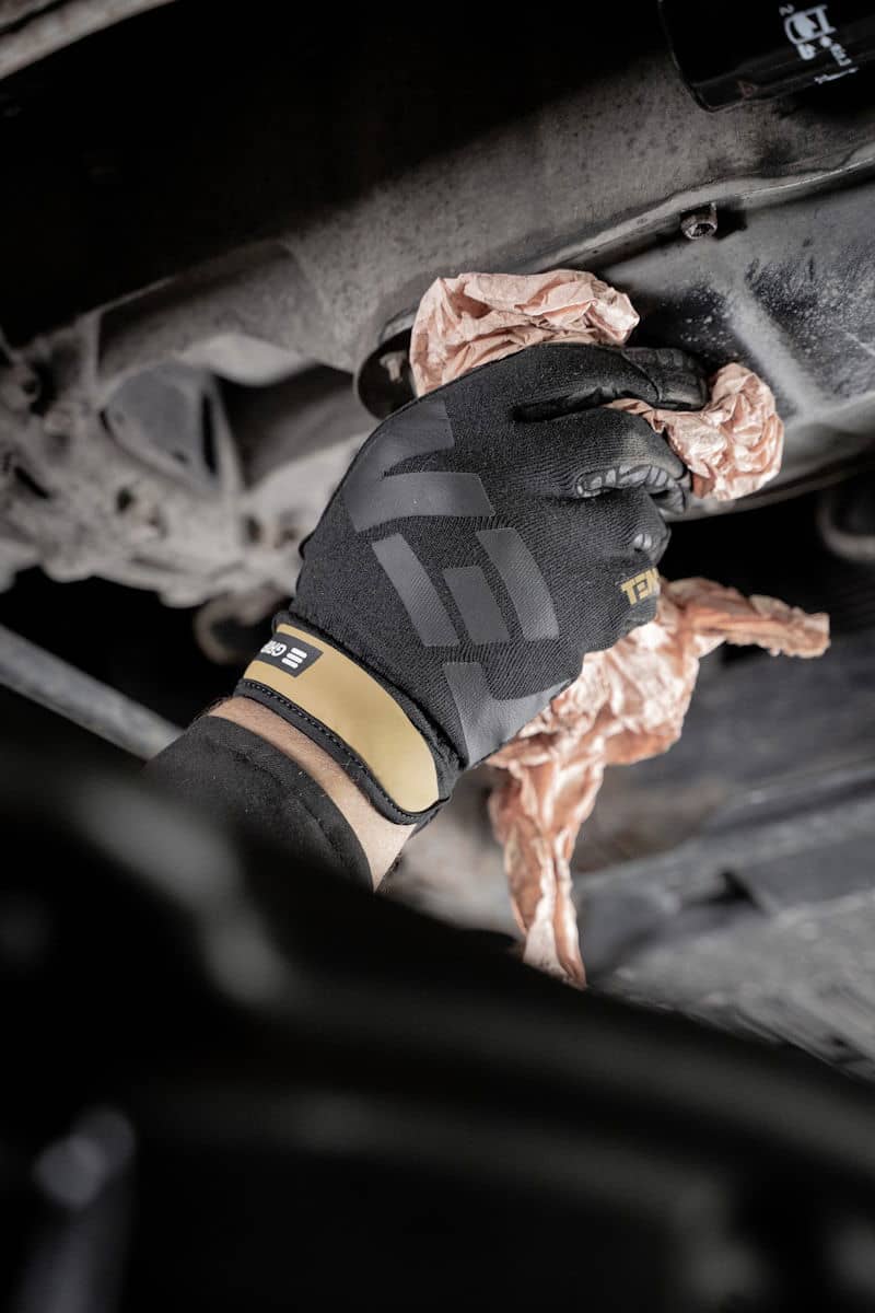 a person in black gloves working on a car